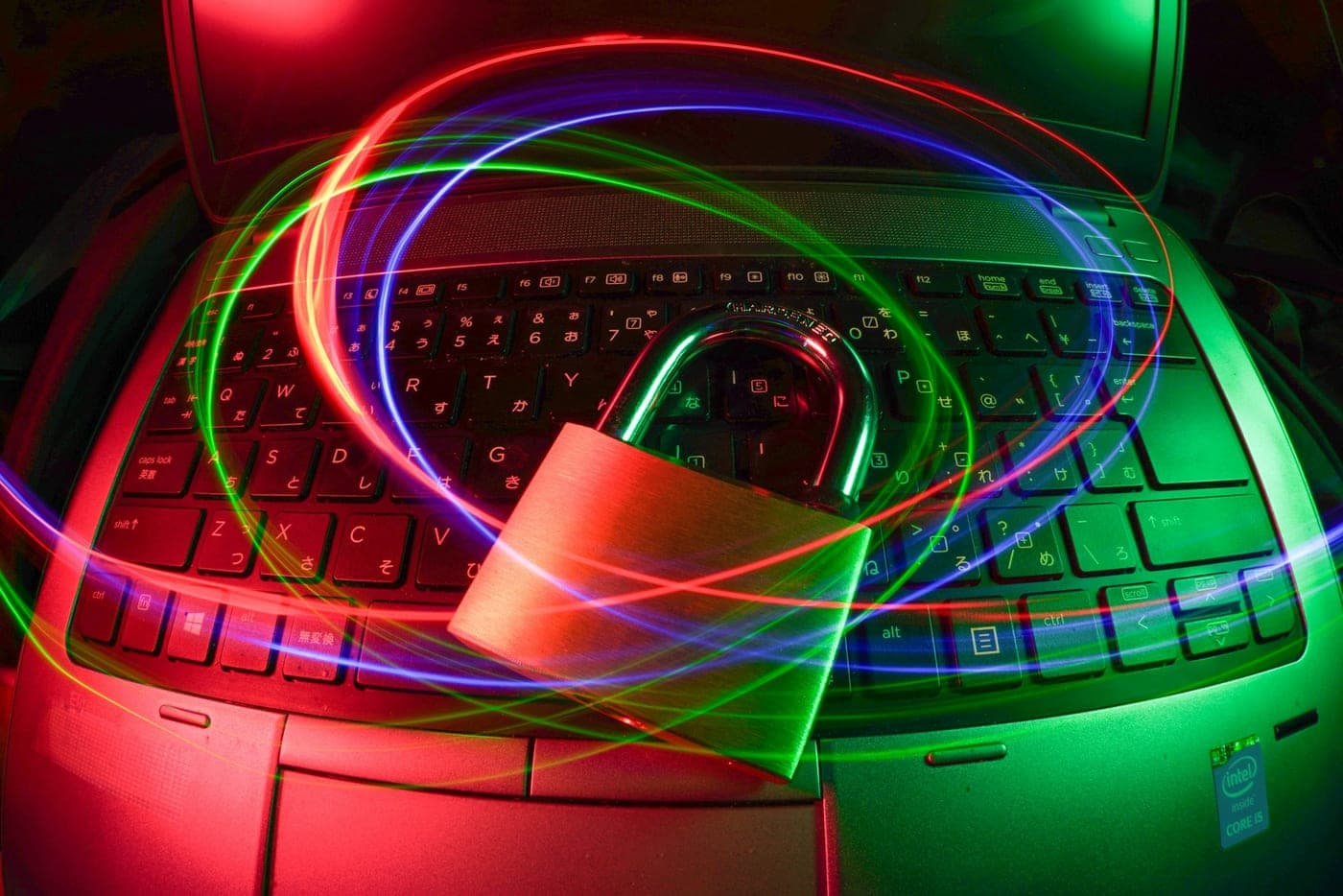 A padlock resting on a laptop, surrounded by light trails, symbolizing data security